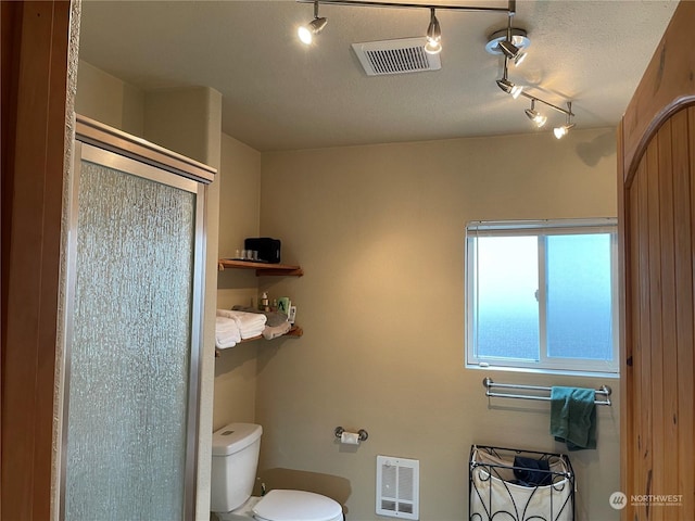 bathroom featuring walk in shower, heating unit, and toilet