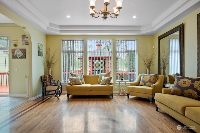 sitting room featuring light hardwood / wood-style floors, a tray ceiling, an inviting chandelier, and plenty of natural light