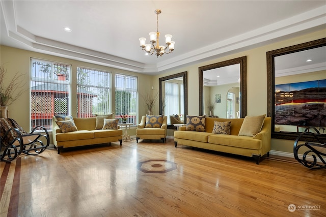 living room featuring light hardwood / wood-style floors, a raised ceiling, and a chandelier