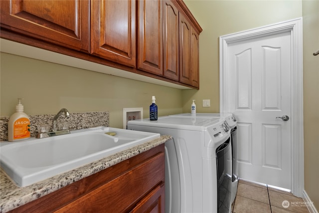 washroom featuring sink, washing machine and clothes dryer, light tile patterned floors, and cabinets