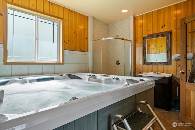 bathroom featuring a shower with door, vanity, wood walls, and tile patterned floors