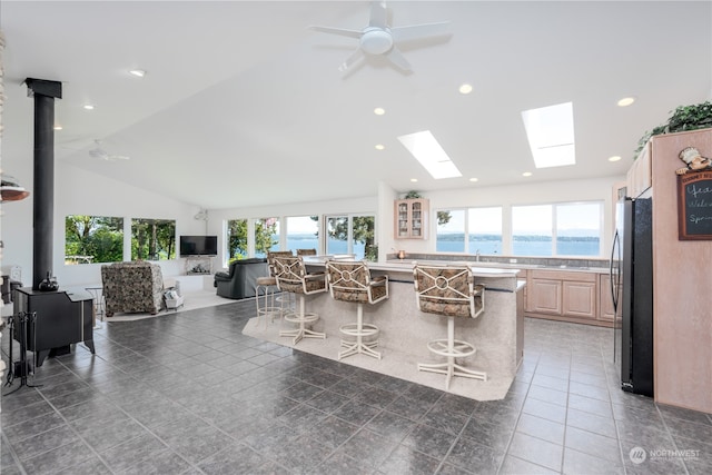 kitchen featuring light brown cabinets, black fridge, a kitchen bar, ceiling fan, and tile flooring