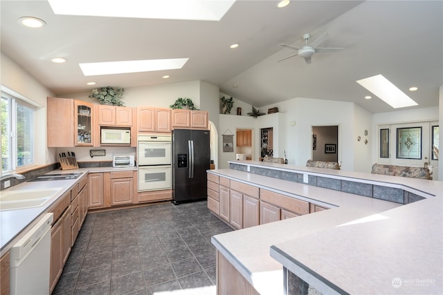 kitchen featuring a skylight, white appliances, ceiling fan, and sink