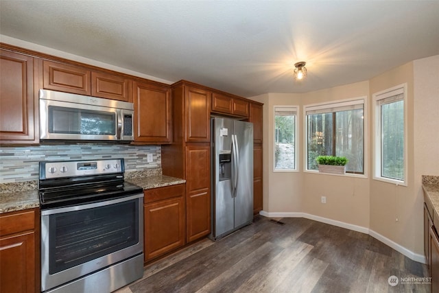 kitchen featuring light stone countertops, appliances with stainless steel finishes, backsplash, and dark hardwood / wood-style floors