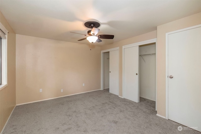 unfurnished bedroom featuring ceiling fan, light carpet, and two closets