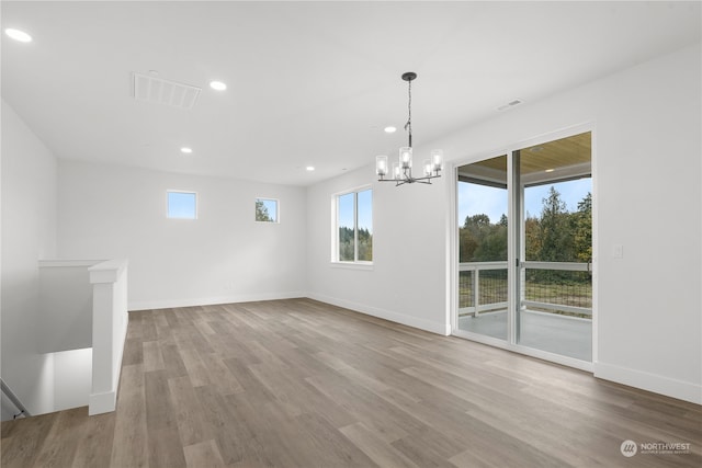 unfurnished dining area featuring light hardwood / wood-style floors and a chandelier