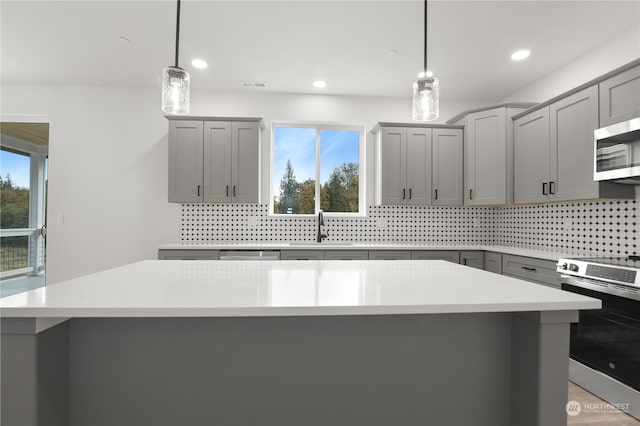 kitchen with appliances with stainless steel finishes, a kitchen island, and pendant lighting