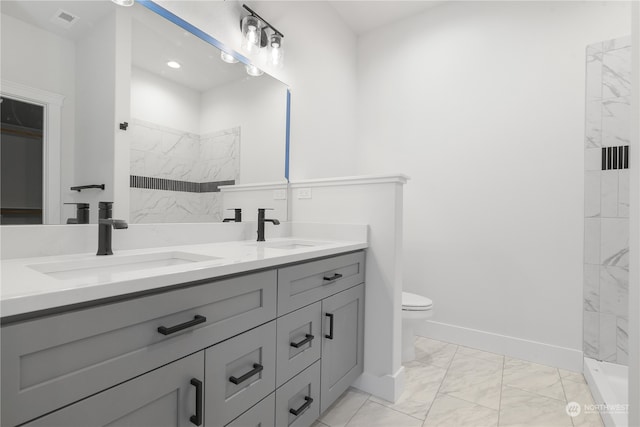 bathroom with tiled shower, vanity, and toilet