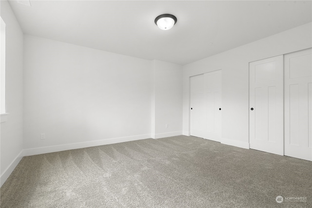 unfurnished bedroom featuring carpet flooring and two closets