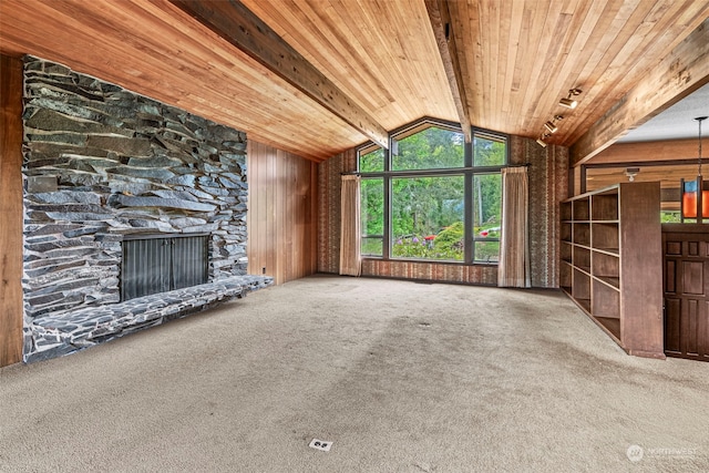 unfurnished living room featuring lofted ceiling with beams, wooden walls, wood ceiling, a fireplace, and carpet floors