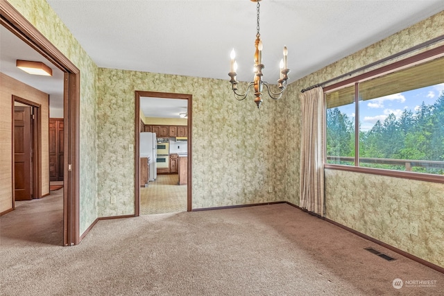 spare room featuring carpet floors and a notable chandelier