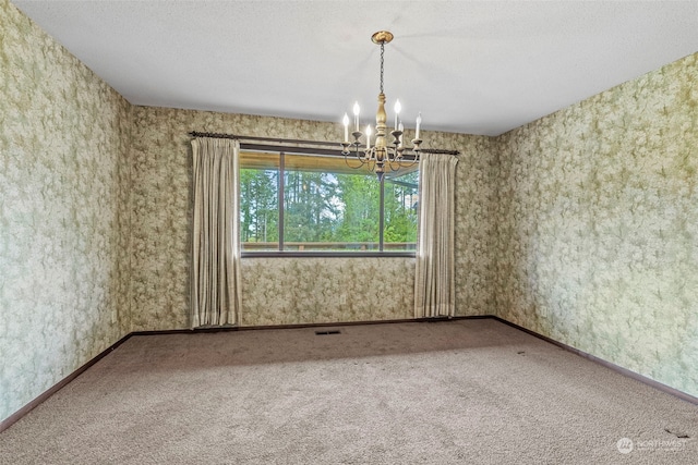 carpeted empty room featuring a chandelier and a textured ceiling