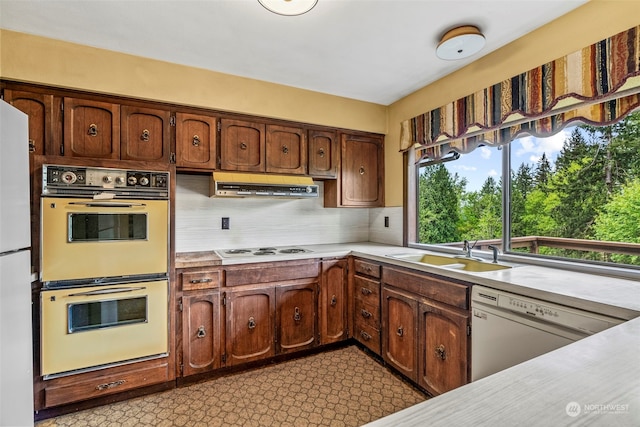 kitchen with white appliances, backsplash, light tile floors, sink, and fume extractor