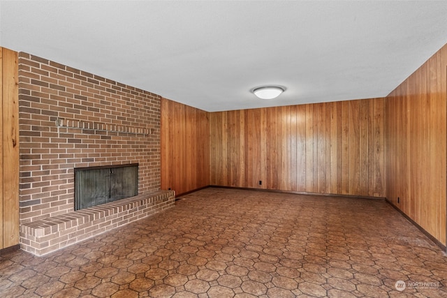 unfurnished living room featuring brick wall, wood walls, tile floors, and a fireplace