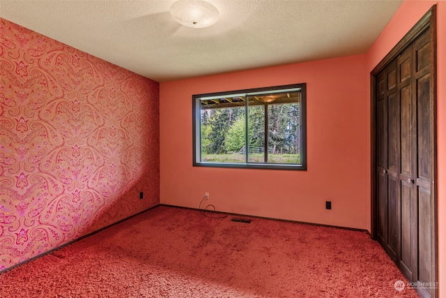 unfurnished bedroom featuring a closet, a textured ceiling, and carpet flooring