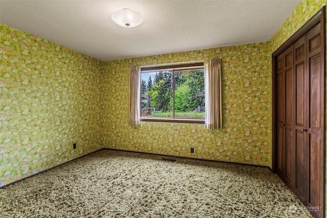 unfurnished bedroom featuring carpet flooring, a closet, and a textured ceiling