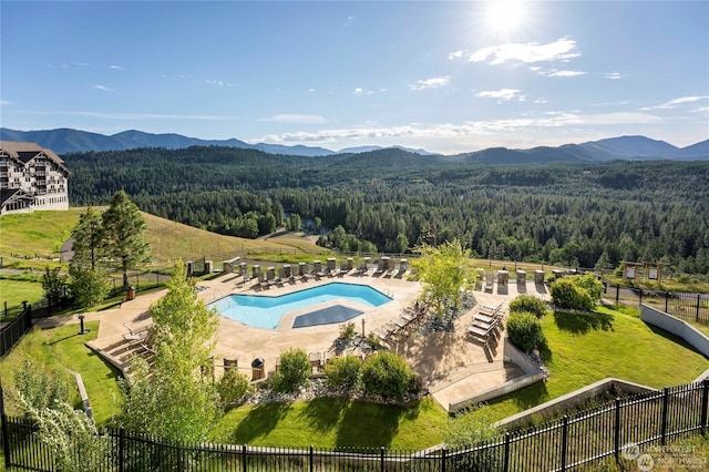 exterior space featuring a patio area, a hot tub, a yard, and a mountain view