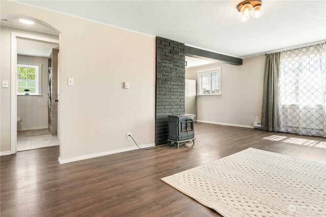 unfurnished living room with brick wall, a wood stove, and dark hardwood / wood-style floors