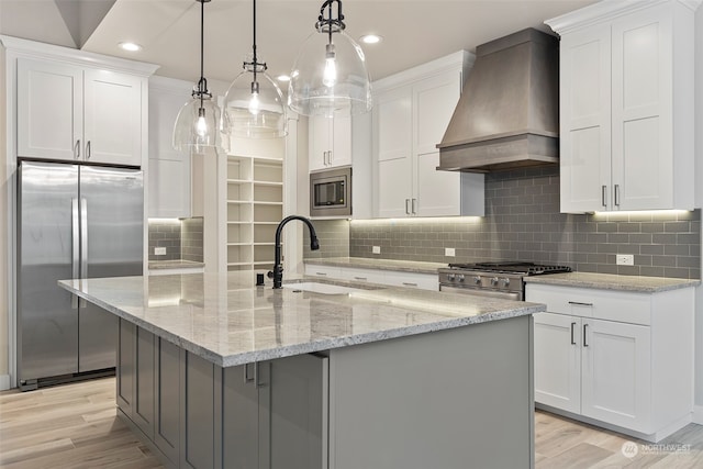 kitchen with premium range hood, white cabinetry, sink, and appliances with stainless steel finishes