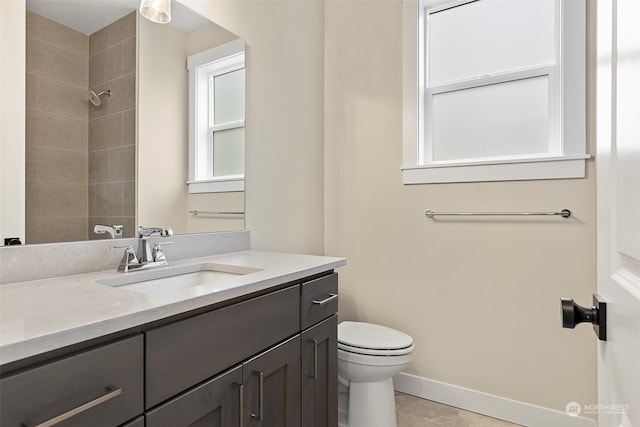 bathroom with toilet, vanity, tile patterned flooring, and tiled shower