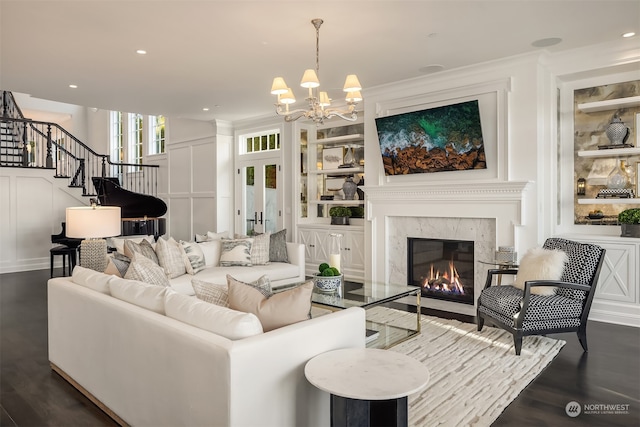 living room featuring a high end fireplace, dark hardwood / wood-style flooring, built in shelves, and a notable chandelier