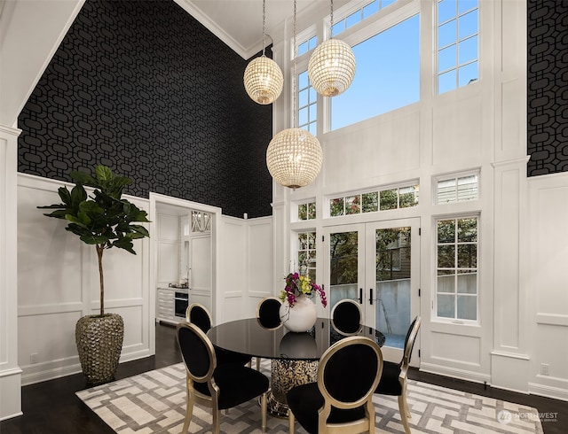 dining area featuring a high ceiling, french doors, ornamental molding, and a healthy amount of sunlight