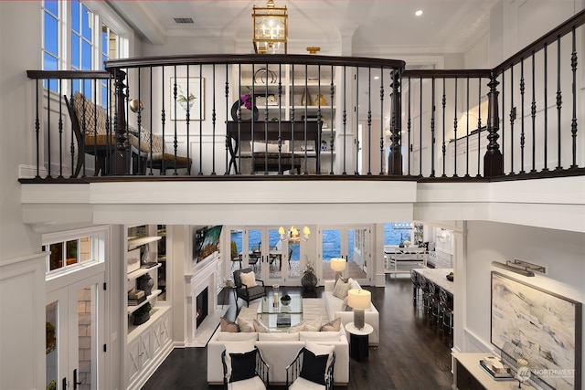 dining room featuring a healthy amount of sunlight, dark wood-type flooring, a chandelier, and ornamental molding