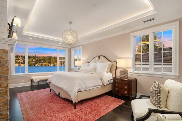 bedroom featuring an inviting chandelier, baseboard heating, a tray ceiling, and dark hardwood / wood-style floors