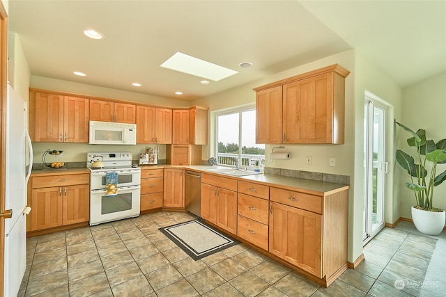 kitchen with a skylight, sink, white appliances, and light tile floors