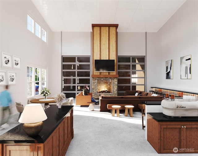 living room with carpet, plenty of natural light, a lit fireplace, and a towering ceiling