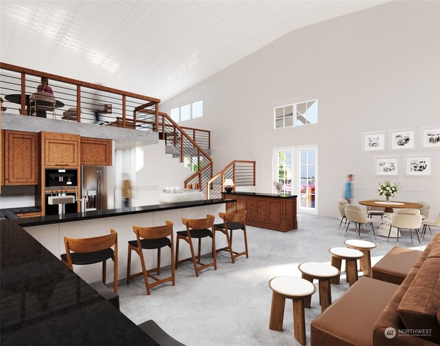 kitchen featuring high vaulted ceiling, light carpet, stainless steel fridge with ice dispenser, brown cabinetry, and a kitchen bar