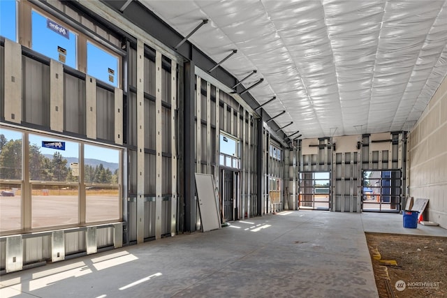 miscellaneous room with a wealth of natural light, unfinished concrete flooring, and a towering ceiling