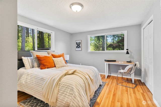 bedroom with hardwood / wood-style floors, a textured ceiling, and a closet