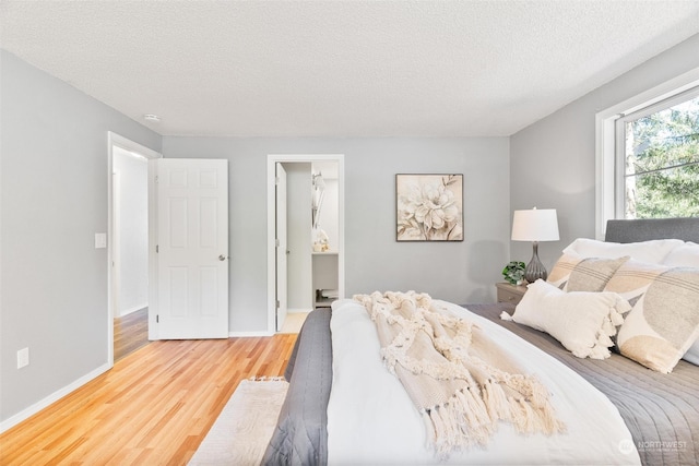 bedroom featuring ensuite bathroom, hardwood / wood-style floors, and a textured ceiling