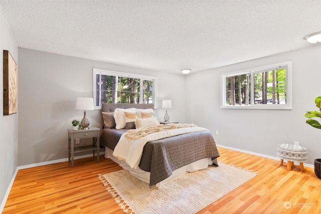 bedroom featuring hardwood / wood-style floors, a textured ceiling, and multiple windows