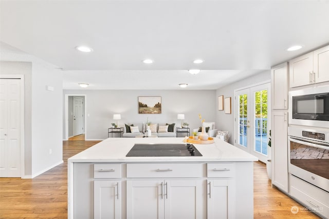 kitchen featuring french doors, light wood-type flooring, white cabinetry, and oven