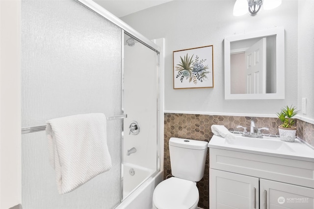 full bathroom featuring vanity, combined bath / shower with glass door, tile walls, and toilet