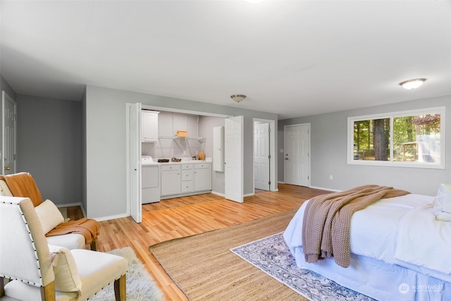 bedroom featuring two closets, separate washer and dryer, and light hardwood / wood-style flooring