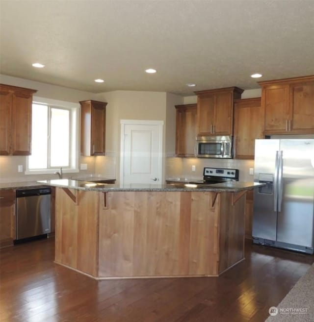 kitchen with a kitchen bar, tasteful backsplash, a center island, dark hardwood / wood-style floors, and stainless steel appliances