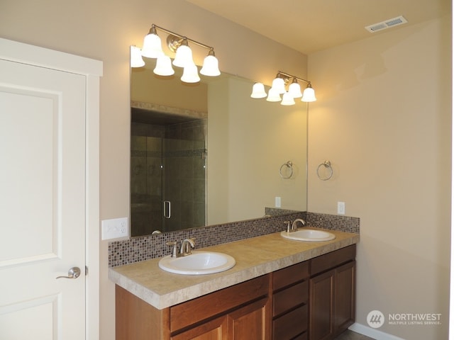 bathroom with tasteful backsplash, vanity, and a shower with door