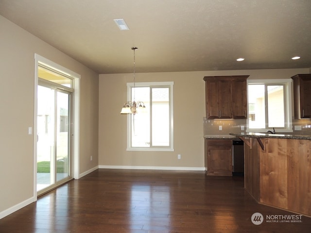 kitchen with dark wood-type flooring, dishwasher, hanging light fixtures, and a wealth of natural light