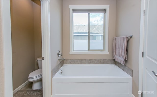 bathroom featuring a tub to relax in, toilet, and a wealth of natural light