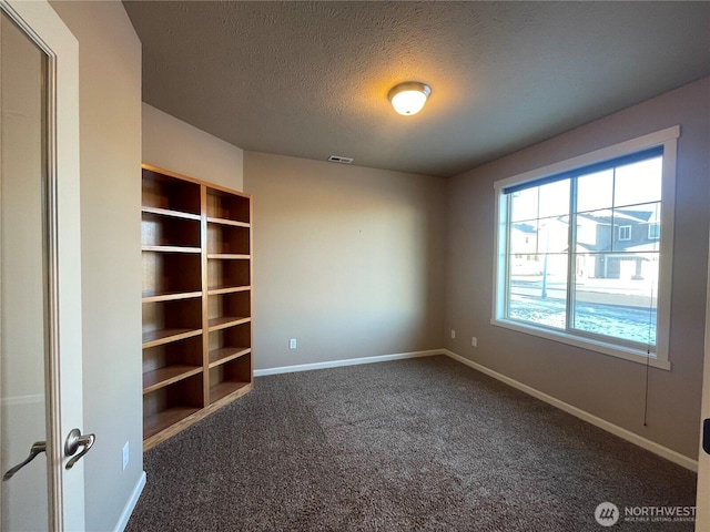 spare room with dark carpet and a textured ceiling