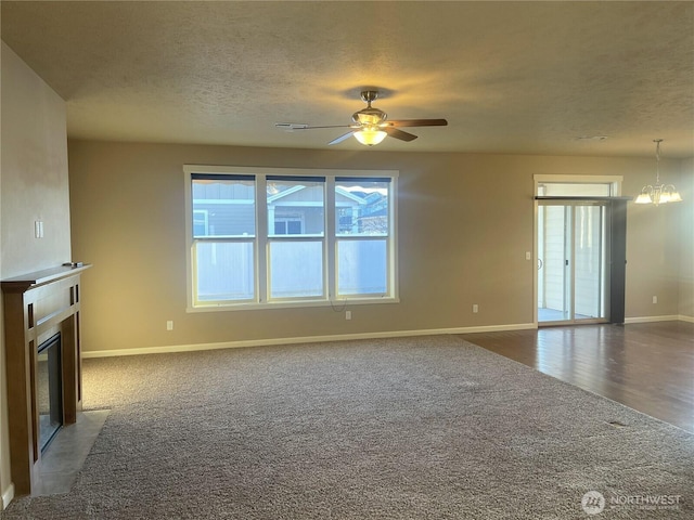 unfurnished living room with carpet, ceiling fan with notable chandelier, and a textured ceiling