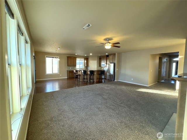 unfurnished living room with ceiling fan and dark colored carpet