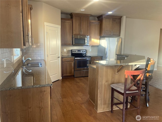 kitchen featuring a kitchen island, stone countertops, appliances with stainless steel finishes, and sink