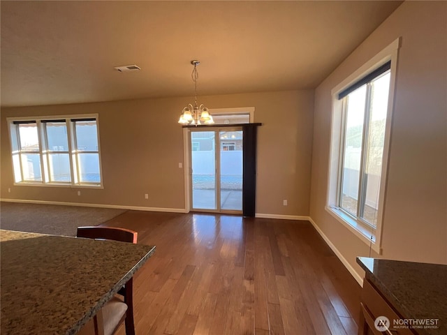 unfurnished dining area featuring hardwood / wood-style floors and a chandelier