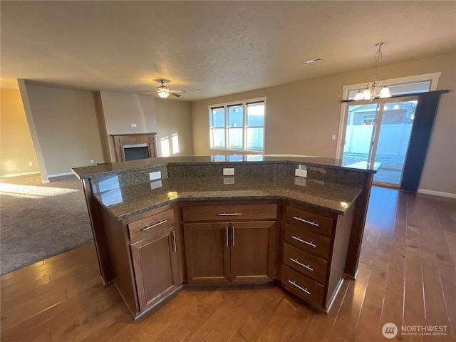 kitchen with dark hardwood / wood-style flooring, hanging light fixtures, and dark stone countertops