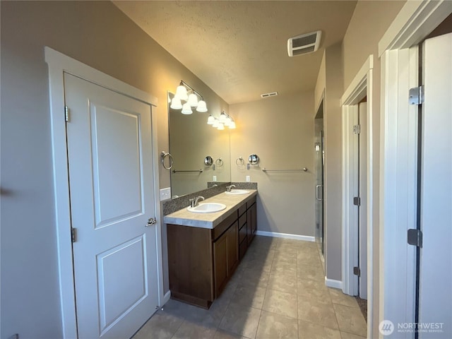 bathroom featuring vanity, tile patterned flooring, a shower with door, and a textured ceiling