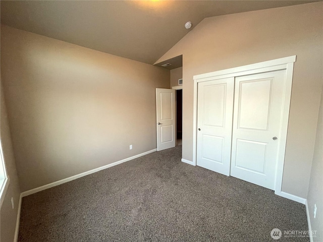 unfurnished bedroom featuring lofted ceiling, dark carpet, and a closet